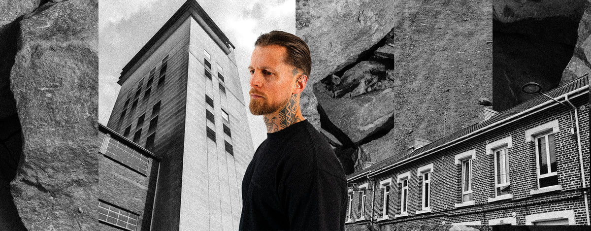 Homme portant un t-shirt noir Gueules Noires devant une architecture industrielle du Nord de la France.